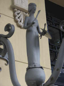 905122 Afbeelding van het beeldje 'kunst' op een van de smeedijzeren buitenlantaarns aan de gevel bij de ingang van het ...